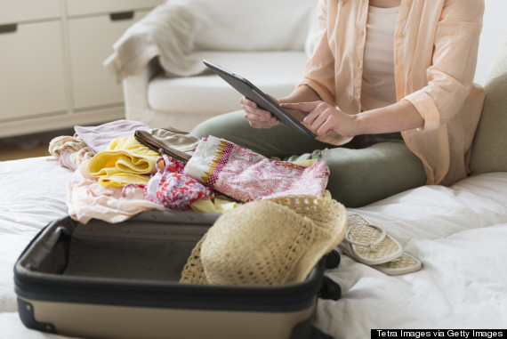 USA, New Jersey, Jersey City, Woman using digital tablet while packing suitcase